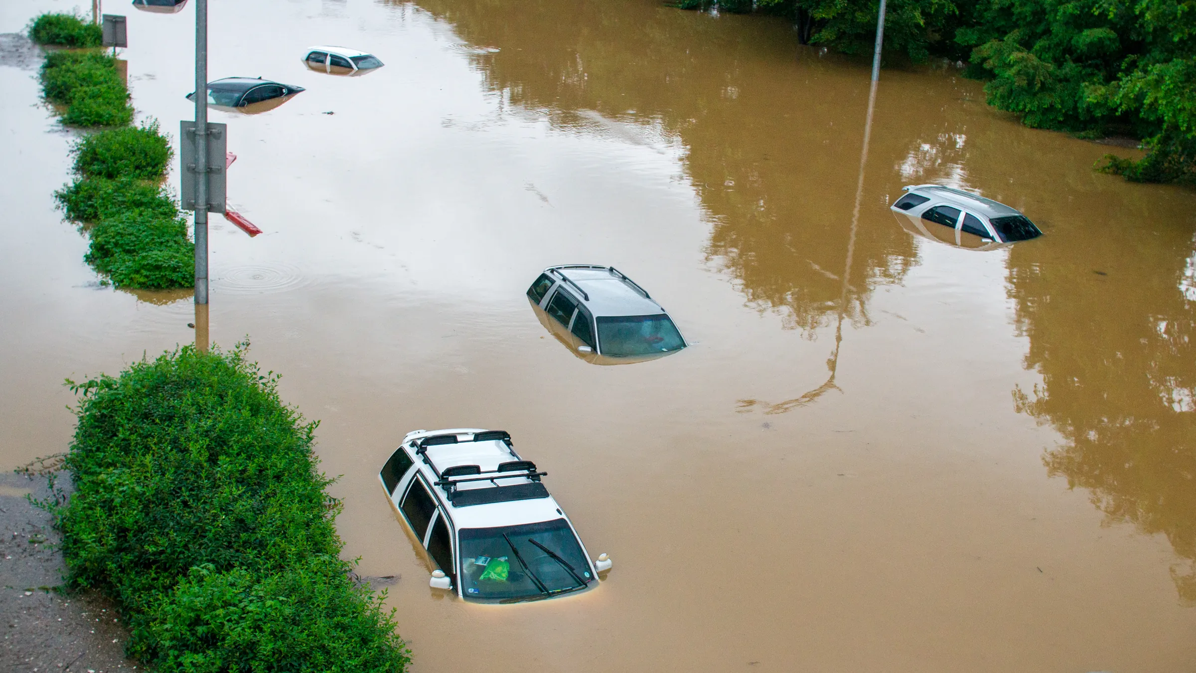 Aerial view of a Texas residential street under floodwater with cars submerged to the windows